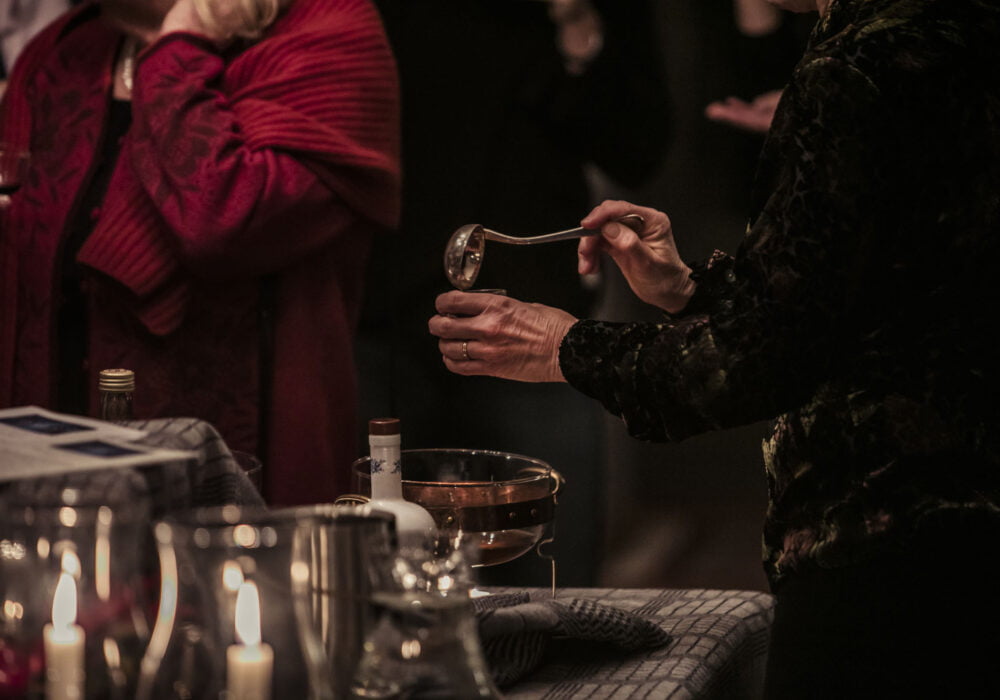 Personer på julfest på Noors slott häller upp glögg.